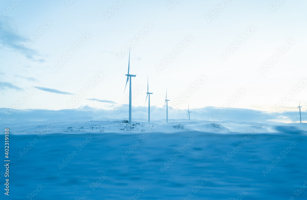 Wind turbines located on snowy terrain under cloudy sky
