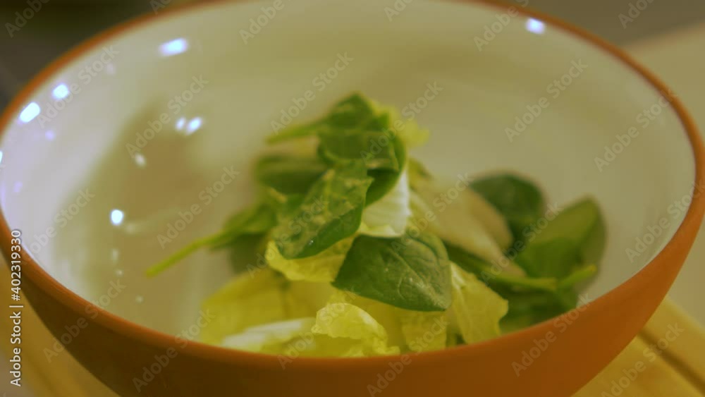 The cook puts fresh green spinach leaves and napa cabbage in to the white clay pot, making pasta salad, handheld close up shot The cook puts fresh green spinach leaves and napa cabbage in to the white clay pot, making pasta salad, handheld close up shot