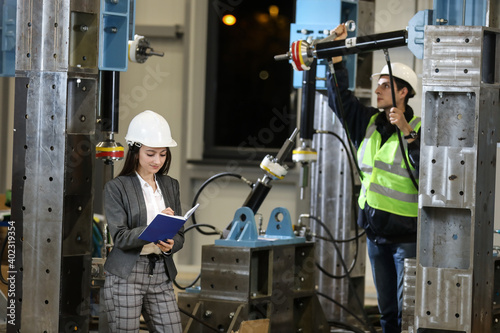 Female project manager in a business suit and white hard hat holds notebook and discusses product details with the chief engineer in a new airplane manufacture. 