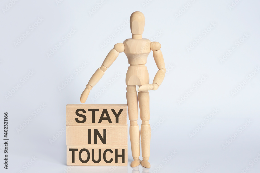 Wooden man shows with a hand text Stay In Touch concept on wooden block Wooden man shows with a hand text Stay In Touch concept on wooden block