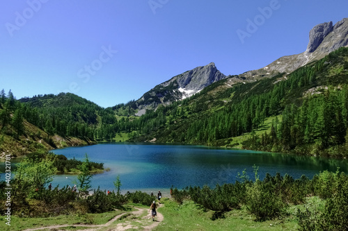 trail with hikers to a blue mountain lake in the summer
