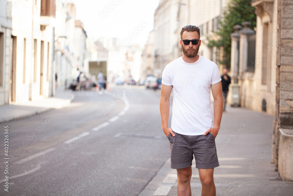 Hipster handsome male model with beard wearing white blank t-shirt and a baseball cap with space for your logo or design in casual urban style Hipster handsome male model with beard wearing white blank t-shirt and a baseball cap with space for your logo or design in casual urban style