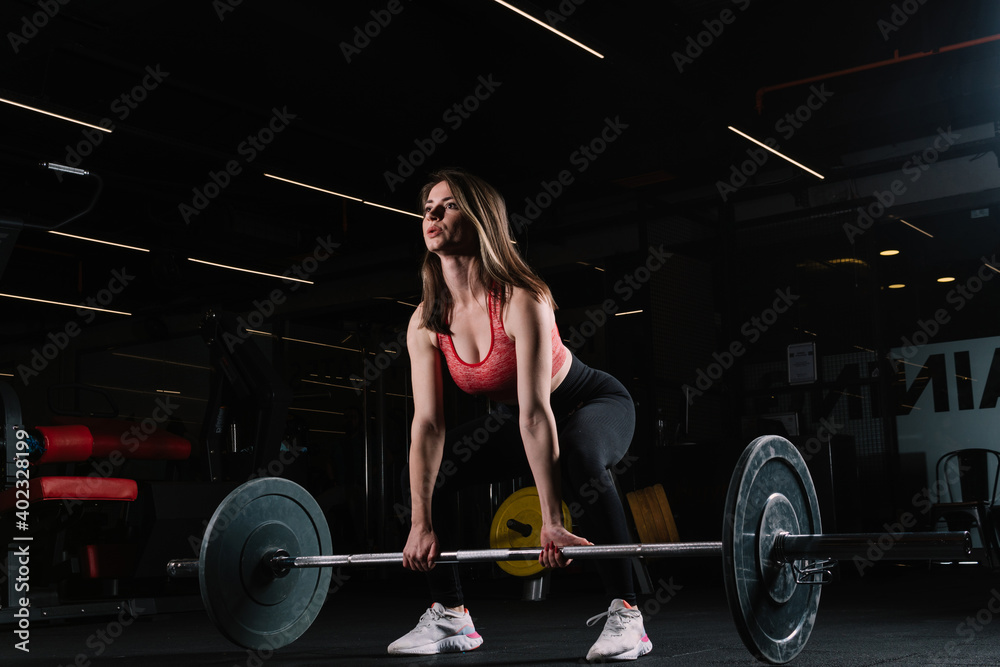 Attractive young sports woman with barbell. Muscular woman in gym doing heavy weight exercises. Young woman doing weight lifting at health club. Attractive young sports woman with barbell. Muscular woman in gym doing heavy weight exercises. Young woman doing weight lifting at health club.
