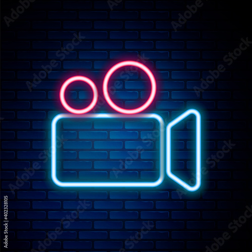 Glowing neon line Movie or Video camera icon isolated on brick wall background. Cinema camera icon. Colorful outline concept. Vector.