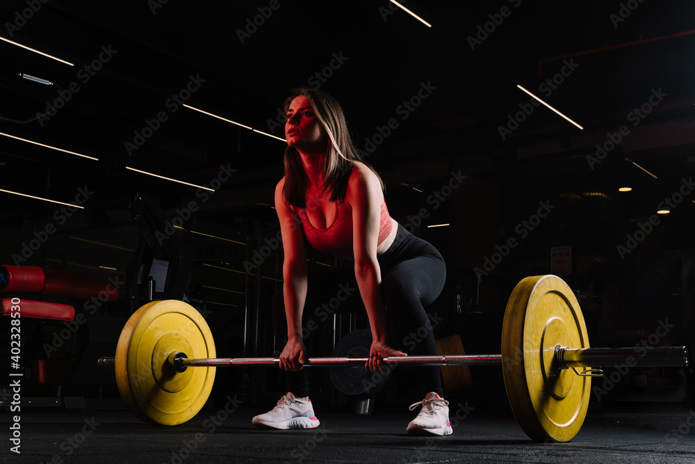 Attractive young sports woman with barbell. Muscular woman in gym doing heavy weight exercises. Young woman doing weight lifting at health club. Attractive young sports woman with barbell. Muscular woman in gym doing heavy weight exercises. Young woman doing weight lifting at health club.