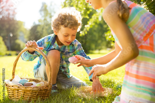Canvas Print Cute boy and girl celebrating Easter, searching and eating chocolate eggs