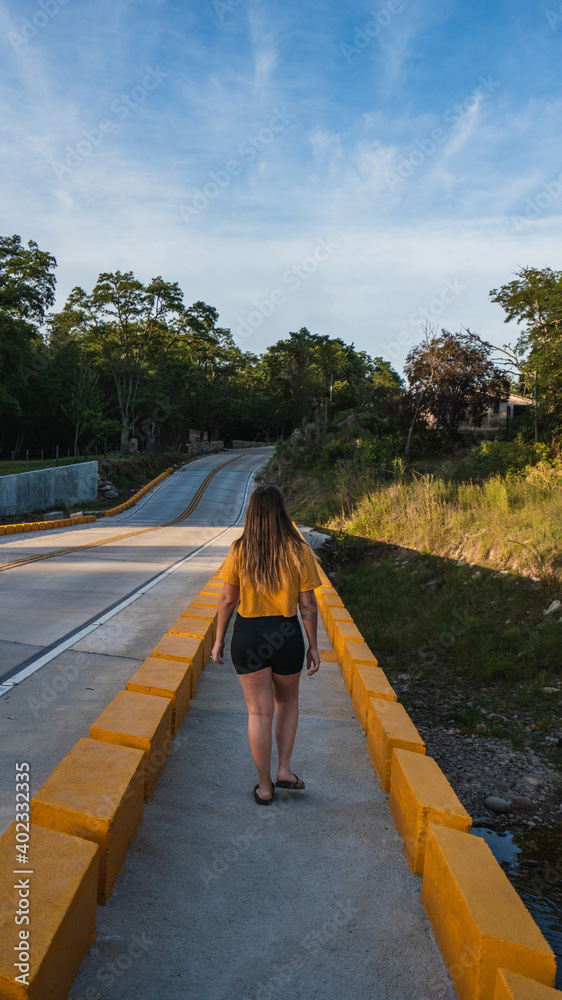 girl dressed in yellow enjoying and playing on a bridge near a river with a background of mountains girl dressed in yellow enjoying and playing on a bridge near a river with a background of mountains