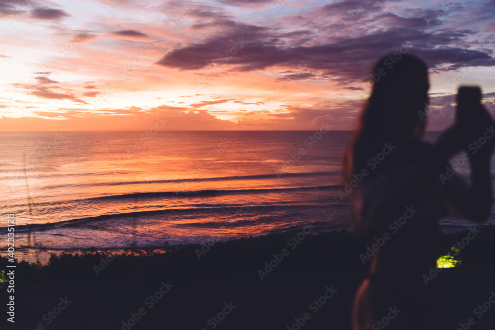 Unrecognizable woman taking photo of sunset