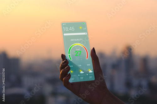 Transparent Smartphone . The Woman Use a futuristic design phone in the city during sunset . air quality design application . future technology and business concept . 