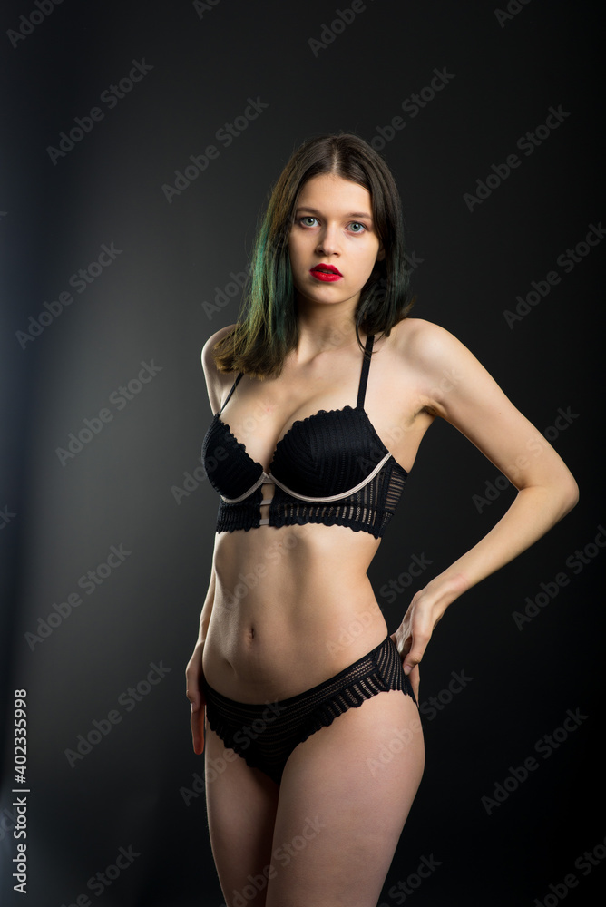 Cute brunette female model posing, wearing black underwear in dark studio
