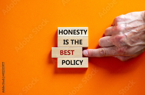 Honesty is the best policy symbol. Wooden blocks. Text 'honesty is the best policy', businessman hand. Beautiful orange background, copy space. Business and honesty is the best policy concept. photo