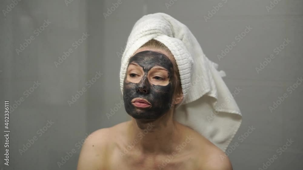 An adult woman applies a cream mask to her face An adult woman applies a cream mask to her face