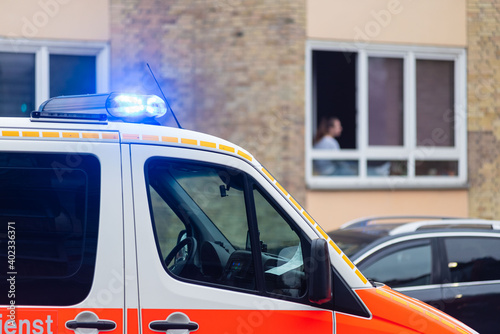 Einsatzfahrzeug der Feuerwehr vor Wohnhaus mit Schaulustiger am Fenster photo