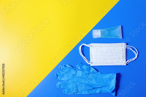 Gloves  a Medical mask  and gel alcohol put on blue and yellow background.