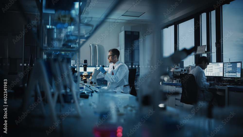 Fototapeta premium Medical Science Laboratory with Diverse Multi-Ethnic Team of Microbiology Scientists Developing Drugs, Medicine, Doing Biotechnology Research. Working on Computers, Analyzing Samples. Evening Work
