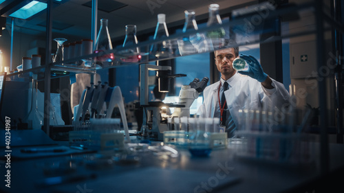 Medical Development Laboratory: Scientist Using Microscope, Analyzes Petri Dish Sample. Pharmaceutical Lab with Specialists Conducting Medicine, Biotechnology Research. Evening Work