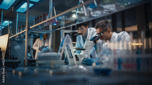 Valokuva Modern Medical Research Laboratory: Team of East Asian and Caucasian Scientists Work on Laptop, do Data Analysis, Use Microscope