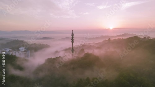4K UHD Cinematic hyperlapse Aerial footage circle view of 5G Communication tower during morning sunrise with clouds, mists and fog