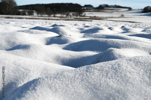 Close-up of a snow covered field. The snow looks like white sand dunes. photo