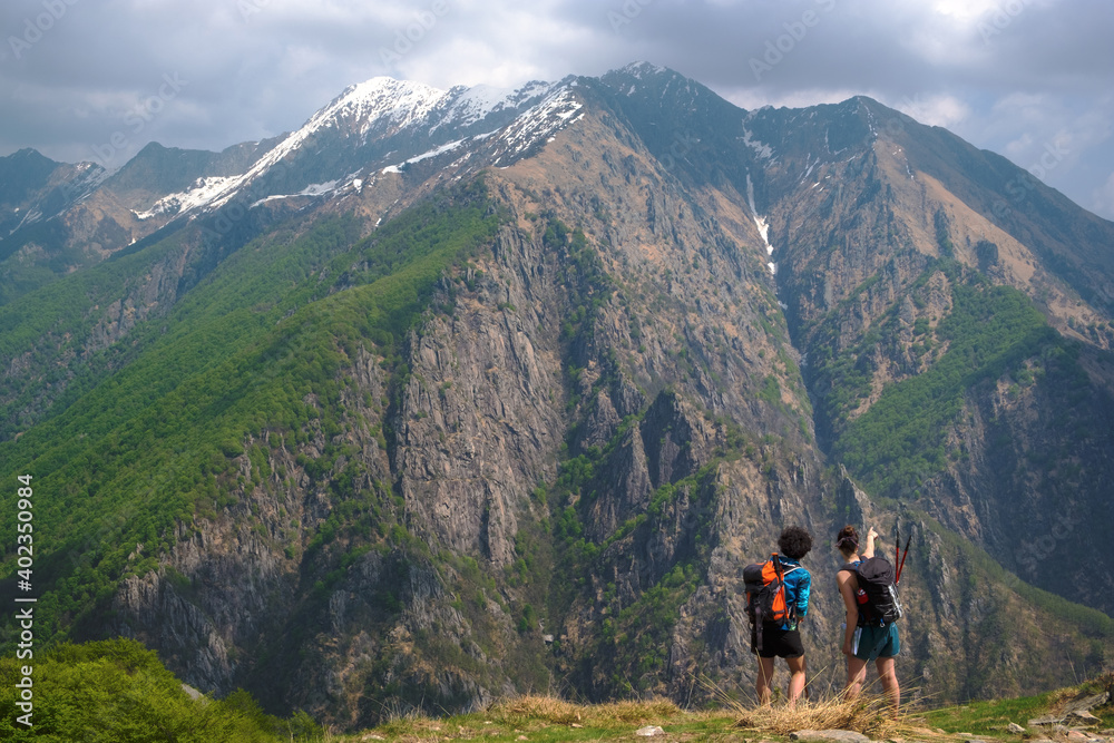 Girls hikers with backpack pointed the mountains to spot  the local fauna on top of a panoramic point, the Val Grande National Park, Europe, Piedmont Italy.
