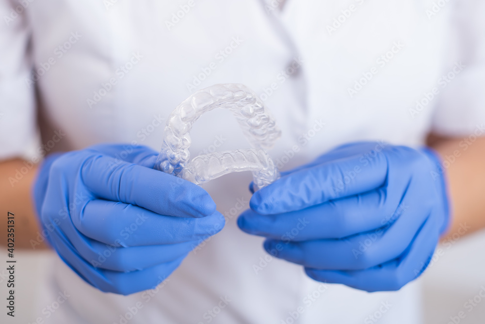 The orthodontist holds the removable transparent retainers