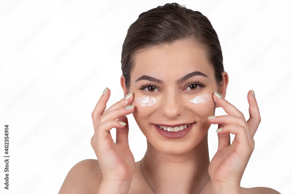 Beautiful female model applying cosmetic cream treatment on white face