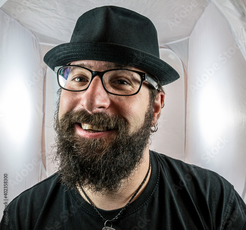 Canvas Print A bearded smiling man in a good mood with black glasses
