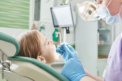 Child to the dentist. Child in the dental chair dental treatment during surgery. Small kid patient visiting specialist in dental clinic.