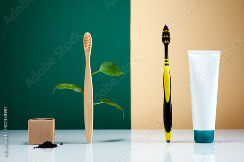 Zero waste, Eco-friendly creative concept. Wooden bamboo toothbrush with leaves VS plastic brush. Natural organic bathroom beauty product.