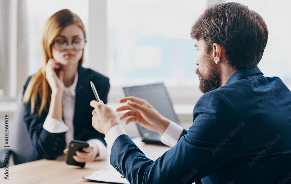 A business man in a suit and a woman communicate at work opposite each other at the table in the office A business man in a suit and a woman communicate at work opposite each other at the table in the office