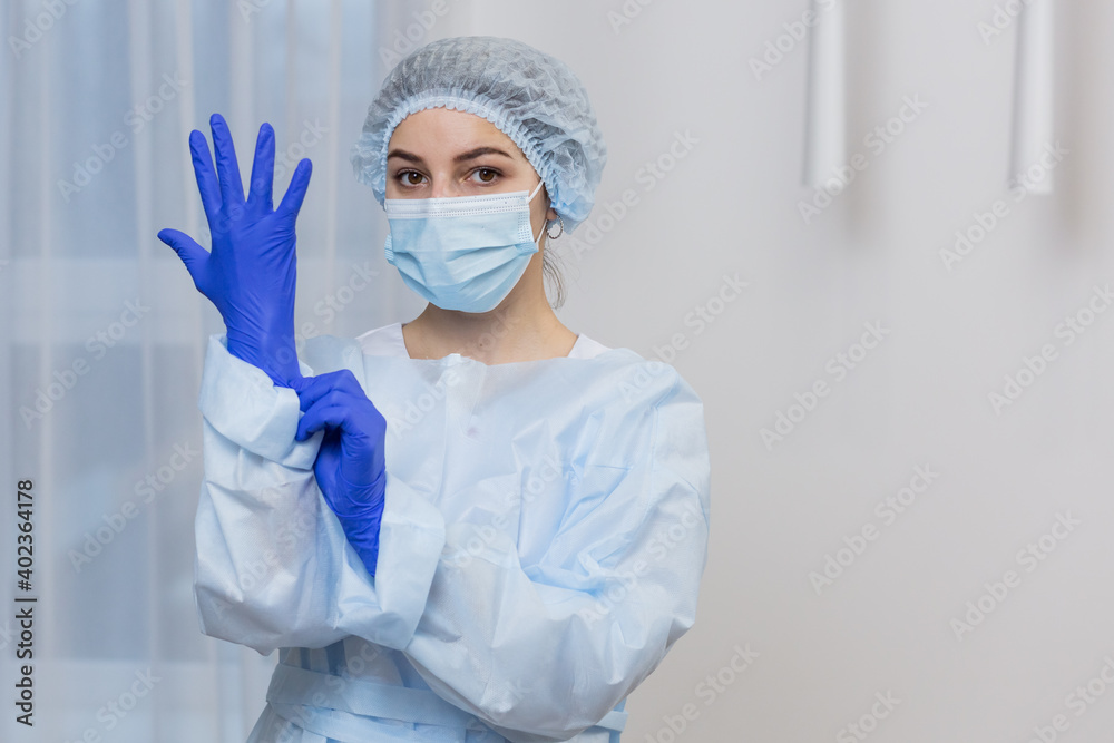 Portrait of a female medic, in a protective blue suit, and a medical mask on her face Portrait of a female medic, in a protective blue suit, and a medical mask on her face