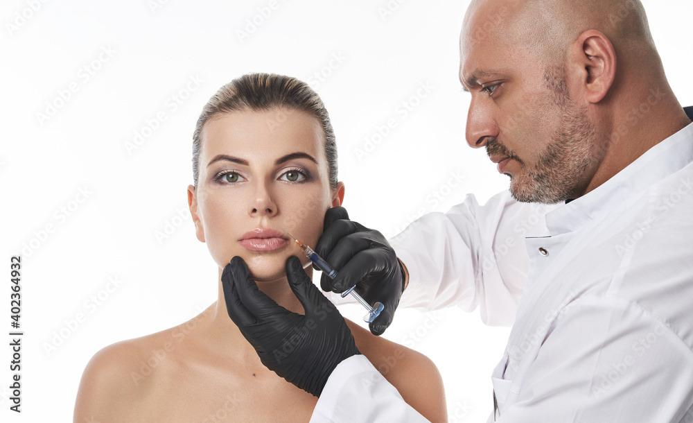 Plasti? surgeon making injection of filler on young woman's lips. Lips augmentation and correction concept Plasti? surgeon making injection of filler on young woman's lips. Lips augmentation and correction concept