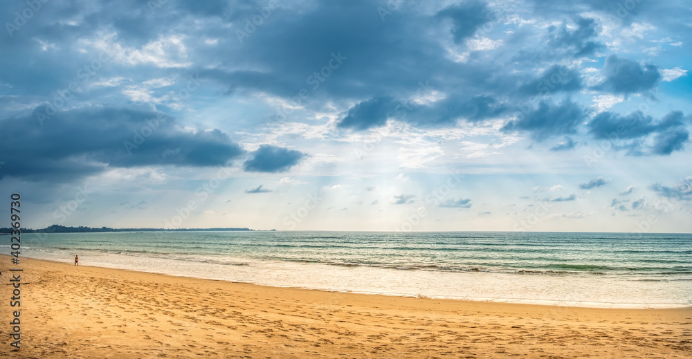 Tropical Thai beach nature landscape at sunset. Empty no people amazing natural sand beach in Thailand, coastline panorama scenery with water sea waves, blue clouds and sun rays Tropical Thai beach nature landscape at sunset. Empty no people amazing natural sand beach in Thailand, coastline panorama scenery with water sea waves, blue clouds and sun rays