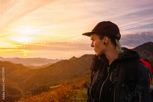 young traveler with a backpack doing a mountain route and watching a majestic sunset. image with copyspace. hiking and travel.