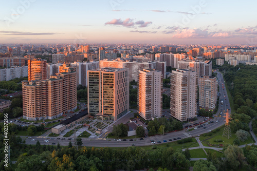 A great metropolis at sunset in the summer. View from the height of a part of the park and the street with large modern houses