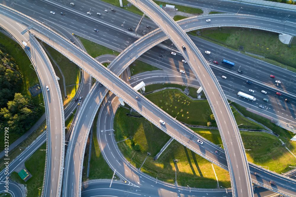 Obraz premium A modern flyover road junction in a large megapolis. Aerial photo from a drone from a altitude. Summer is a sunny day, sunset. 
