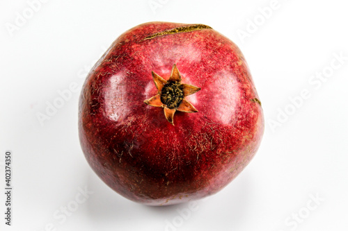 Red ripe pomegranate fruit against a white background. Anthers on ripe fruit up close. Rind outer skin of pomegranate. Macro of pomegranate fruit. Picture from top to bottom.