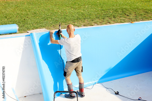 Photo A worker welds plastic cover for water pool