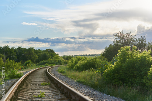 Railroad turns among the green trees in the summer