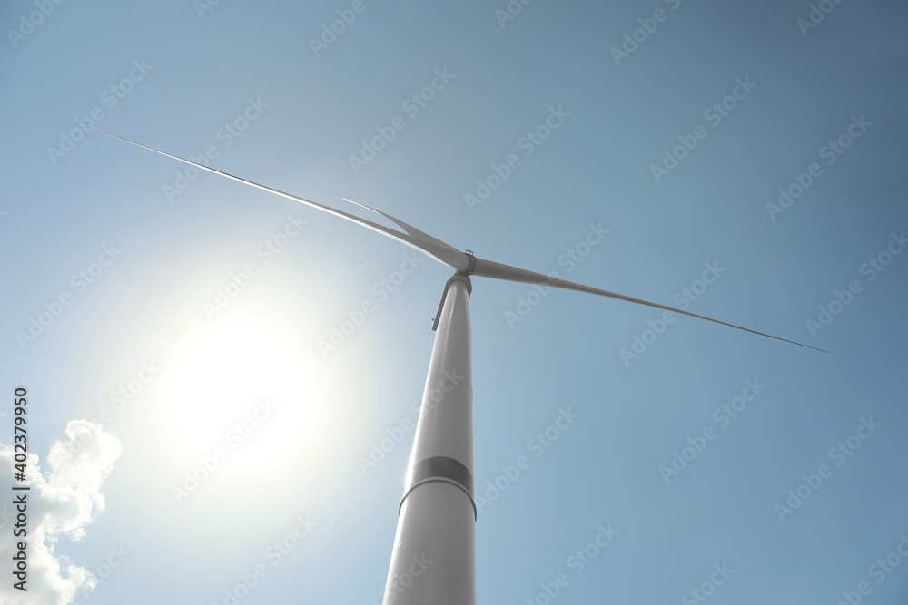 Modern wind turbine against blue sky, low angle view. Energy efficiency Modern wind turbine against blue sky, low angle view. Energy efficiency