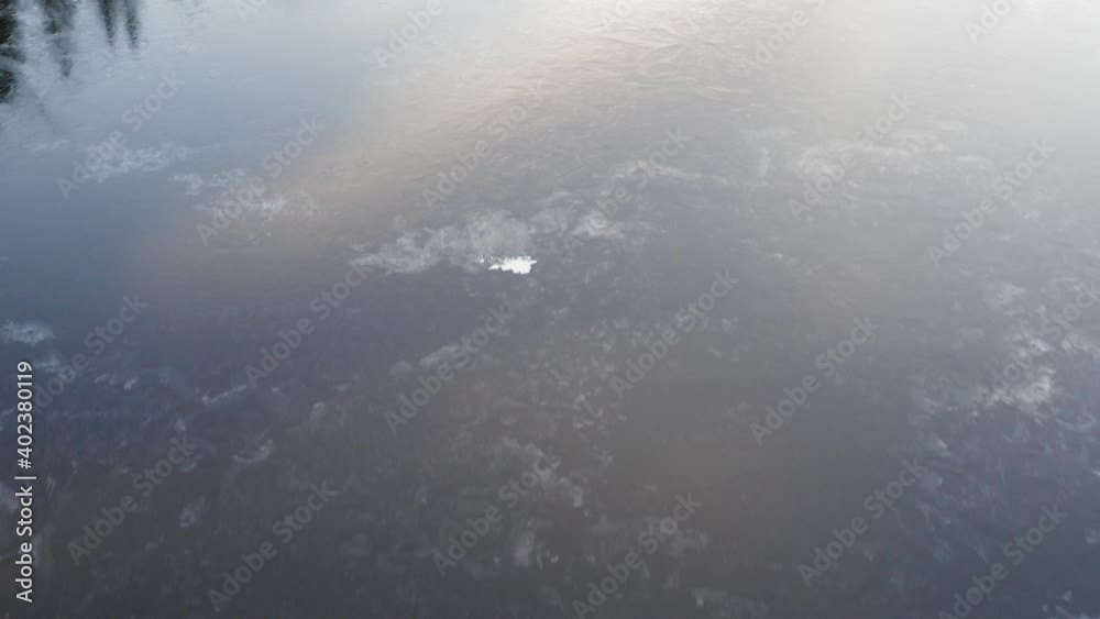Aerial view flying over frozen lake surface reflecting forestry and skyline Aerial view flying over frozen lake surface reflecting forestry and skyline