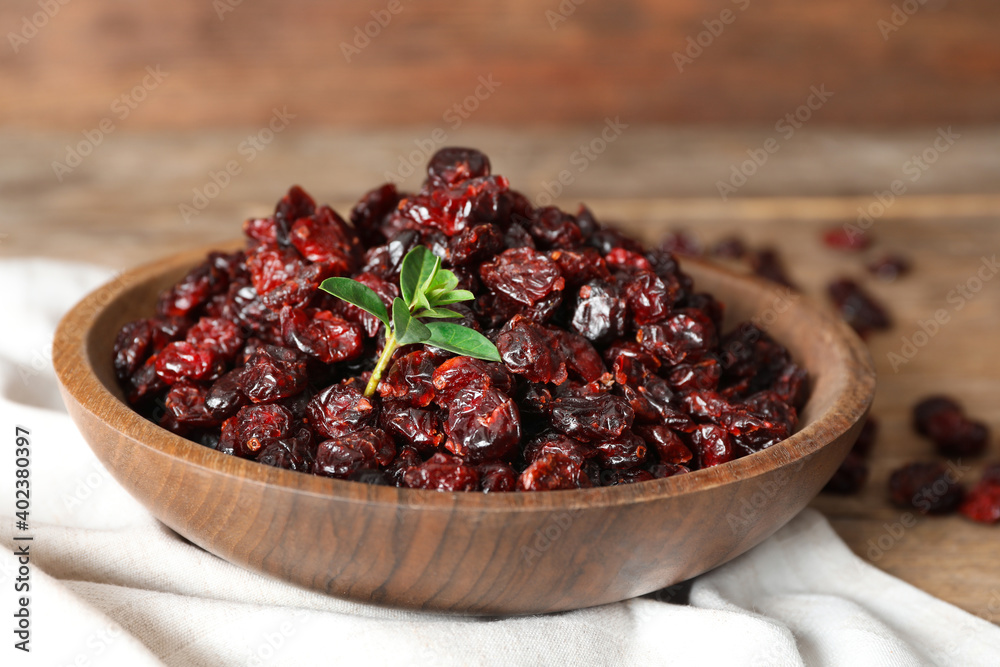 Dried cranberries in bowl on wooden table, closeup Dried cranberries in bowl on wooden table, closeup