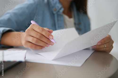 Woman writing letter at table indoors, closeup