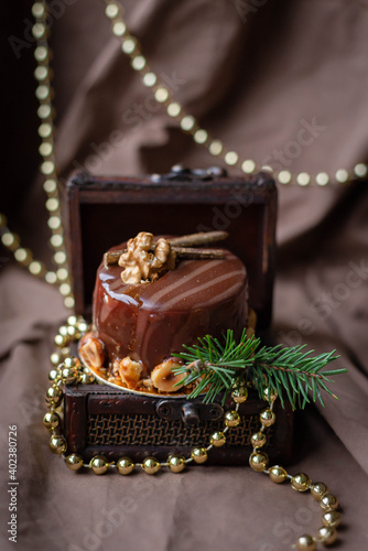 postcard, food photo beautiful festive New Year's cake with nuts, in a box, on a brown background, lights, decor, tre