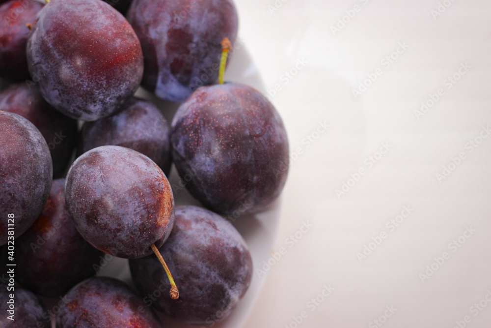 Appetizing ripe plums on a white background with copy space