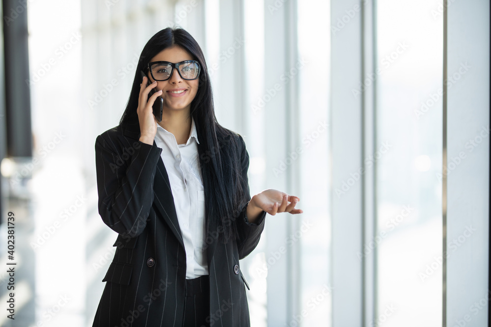 Young businesswoman talking on mobile phone at her working place