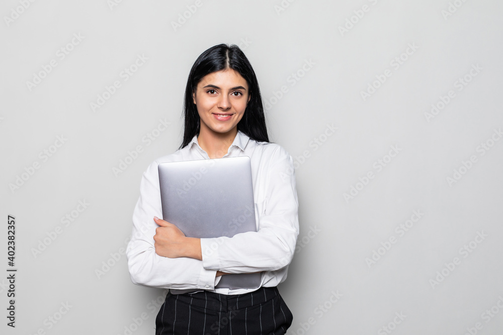 Portrait of a businesswoman holding laptop computer and looking away isolated over white background