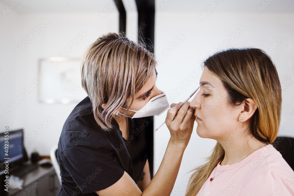 Latin Cosmetologist preparing to mexican woman for eyebrow permanent makeup procedure in Mexico, Microblading closeup Latin Cosmetologist preparing to mexican woman for eyebrow permanent makeup procedure in Mexico, Microblading closeup