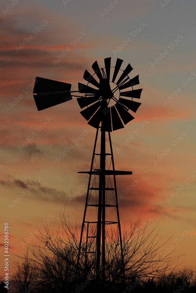 windmill at sunset with colorful clouds out in the country north of Hutchinson Kansas USA. windmill at sunset with colorful clouds out in the country north of Hutchinson Kansas USA.