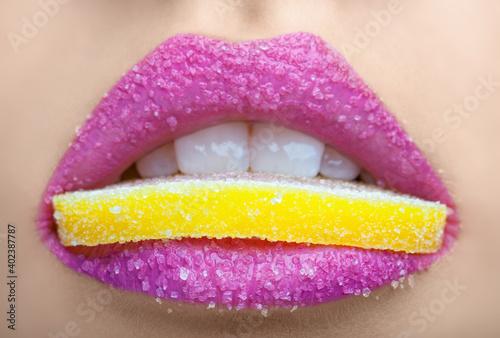 Fotografie Beautiful young girl with pink lips eats a slice of lemon